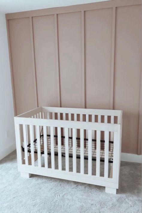 A photo of a board and batten accent wall in the color insightful rose by sherwin Williams as an accent wall in a nursery room for a baby girl Light Pink Nursery Accent Wall, Neutral Nursery With White Crib, Vertical Wood Accent Wall Nursery, Mauve Pink Accent Wall, Nursery Accent Wall Color, Light Mauve Nursery, Cabbage Rose Sherwin Williams Nursery, Blush Board And Batten Wall, Mauve Shiplap Wall