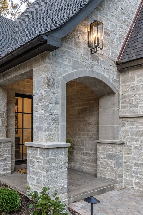 Natural stone luxury dream home features sprawling facade, garage, & front door portico entrance with cut stone accents. The elegance is further enhanced by modern exterior lighting and chandelier, wood backyard decks, outdoor living firepit seating area, and walkway stone pavers. DIY https://www.buechelstone.com/masonry/ how to install stone veneer (mortar / dry stacked stone / exterior & interior stone veneer). Buy stone veneer! Front Door Portico, Grey Stone House, Door Portico, Garage Front Door, Modern Exterior Lighting, Buechel Stone, Stone Veneer Exterior, Stone Exterior Houses, Exterior Houses