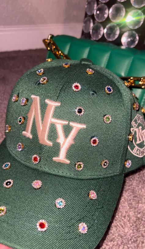 Adjustable NY Custom Bedazzled Hat customed by ShanayCosmetics Comes in 2 colors: Black or Green More colors COMING SOON....  PLEASE KEEP IN MIND THAT I AM NOT RESPONSIBLE FOR ANY DELAYS WITH SHIPPING ONCE I HAVE DROPPED YOUR PACKAGE OFF AT THE POST OFFICE! THAT IS OUT OF MY CONTROL. PLEASE BE AWARE I AM NOT RESPONSIBLE FOR ANY LOST, DAMAGED OR STOLEN PACKAGES!! Bedazzled Clothing, Diy Leather Hat, Bedazzled Hat, Custom New Era Hats, Customized Hats, Bedazzled Stuff, Swag Items, Rhinestone Hat, Bling Hat