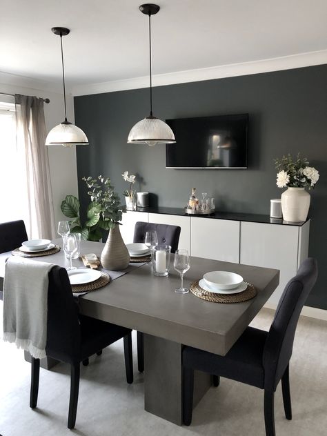 This solid concrete dining table still manages to look elegant in this sophisticated dining room, featuring dark walls and faux foliage, with industrial style pendant lights. The industrial touches are perfectly balanced with the more natural touches such as the curtains and blanket details. Concrete Table Decor, Dining Room Feature Wall, Grey Dining Tables, Grey Dining Room, Concrete Dining Table, Dinning Room Design, Stone Dining Table, Small Kitchens, Concrete Table