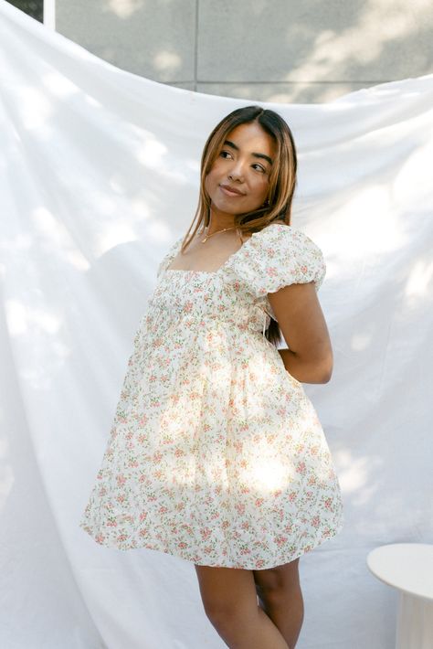 Our Pixie Dusted Dress is a mini cream babydoll dress with a small ditsy pink floral pattern. It displays a square neckline, slight puff sleeves, and subtle pleating throughout the bust for a fitted look. Has an adjustable back with a criss cross strapping detail. It also features a zipper closure for easy on and off access, fully lined, and a flowy babydoll fit below the bust. Has pockets too! Model wears a size x-smallModel is 5'2"100% Cotton / 100% Rayon Measurements:Bust: XS - 26" / S - 27" Floral Puff Sleeve Mini Dress, Cream Babydoll Dress, Cute Dresses For Church, Short Flower Dress, Cute Sundresses, Castle Collection, Short White Dresses, Baptism Dresses, Beachy Dresses