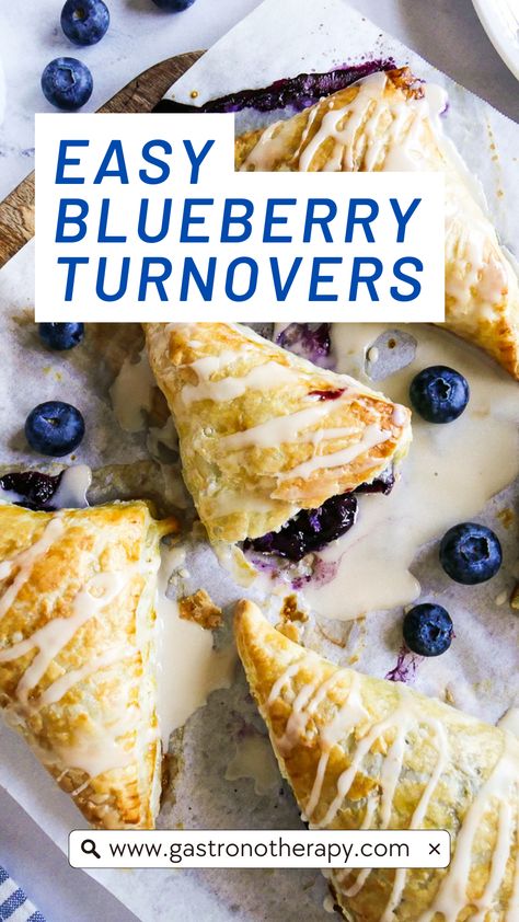 Five blueberry turnovers arranged on parchment paper with icing and fresh blueberries. Easy Blueberry Turnovers, Puff Pastry Recipes Turnovers, Blueberry Turnovers With Pie Crust, Easy Recipes Using Frozen Puff Pastry, Blueberries Puff Pastry, Ways To Use Frozen Blueberries, Puff Pastry With Blueberries, Puff Pastry Frozen Berries, Fruit Turnovers With Pie Crust