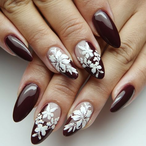 Step up your nail game with this stunning burgundy and floral design! Featuring a mix of deep burgundy and soft nude shades, the intricate white floral patterns add a touch of elegance and sophistication. Perfect for any season, this trendy almond shape manicure combines bold colors with delicate details, making it ideal for special occasions or everyday glam.  #septembernails #fallnails Burgundy Nails With Flowers, Burgundy And White Nail Designs, Burgundy Floral Nails, Burgundy And White Nails, Almond Shape Manicure, Burgundy Nail Art, Everyday Glam, September Nails, Burgundy Nails