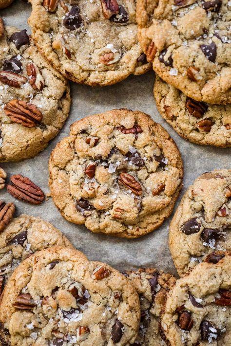 Brown Butter Pecan Chocolate Chip Cookies have a crispy-chewy texture, the irresistible crunch of pecans, and the rich sweetness of chocolate chips. Made with toasty brown butter for a touch of warmth, these cookies are topped with a sprinkle of flaky sea salt, elevating their flavor to new heights. Brown Butter Pecan White Chocolate Chunk Cookie, Snacks With Pecans, Chewy Oatmeal Pecan Cookies, Pecan Snickerdoodle Cookies, Brown Butter Walnut Cookies, Carmel Pecan Chocolate Chip Cookie, Brown Butter Cookie Dough, Chocolate Praline Cookies, Brown Butter Pecan White Chocolate Chunk