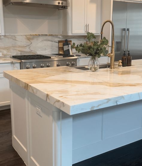 Learn about all the different types of white kitchen countertops. Get inspired by kitchen design ideas for different styles of white kitchens Backsplash With White Marble Countertops, White With Gold Quartz Countertop, Full Backsplash Quartz, White Kitchen Cabinets With Marble Countertops, White Gold Granite Countertops, White And Gold Quartzite Countertops, White Kitchen With Quartzite Countertops, White Cabinets Kitchen Countertop Ideas, Calcutta Gold Quartz Countertops And Backsplash