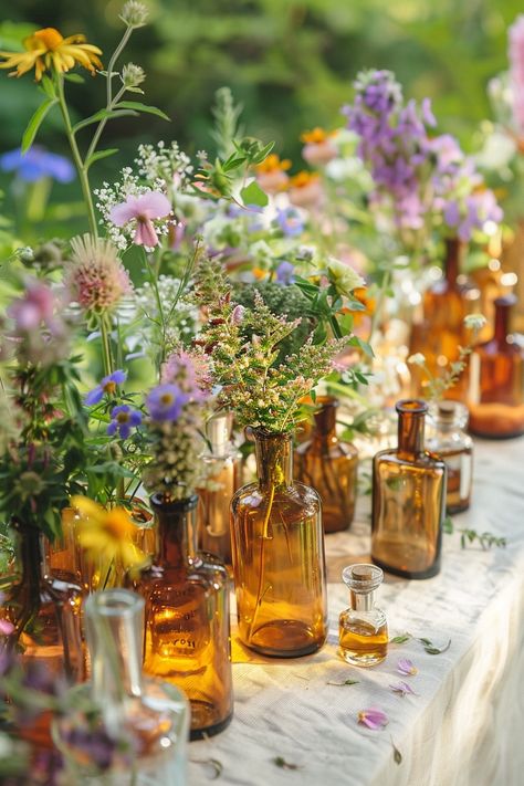 Elevate your wedding decor with a unique touch of the past. These vintage perfume bottles turned vases are filled with an array of herbs and wildflowers, perfect for a bohemian-themed celebration. 🌿🌼💐 A touch of nostalgia meets natural beauty for your special day. #WeddingInspiration #BohoWedding #CenterpieceIdeas #VintageDecor #FloralDesign #DIYWedding #EventStyling #WeddingFlowers Vintage Vases Wedding Centerpieces, Boho Wedding Table Flowers, Vintage Table Decorations Wedding, Outdoor Wedding Floral Decorations, Wild Flower Centerpieces Wedding Simple, Wedding Decor Wildflowers, Wildflowers Wedding Theme, Wildflower Vintage Wedding, Dried Flower Table Decor