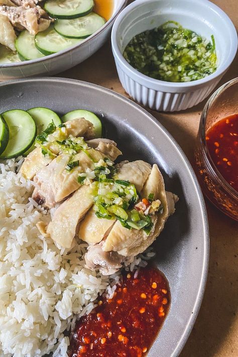 On a grey plate is a serving of rice topped with chicken, ginger scallion sauce, spicy sauce, and sliced cucumbers. Next to the plate is an extra serving of ginger scallion sauce in a ramekin and extra serving of spicy sauce in a clear bowl. Hainese Chicken Rice, Singapore Chicken Rice Recipe, Hainese Chicken, Chicken Rice Easy, Ginger Rice Recipe, Singaporean Rice, Singapore Chicken Rice, Hainan Chicken Rice, Ginger Chicken Recipes