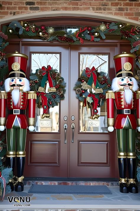 Festive front door decor featuring two majestic nutcracker statues, wreaths with red bows, and lush garlands adorned with ornaments. Front Porch Christmas Decor Nutcracker, Front Door Nutcracker, Christmas Nut Cracker, Nutcracker Outdoor Decor Christmas Yard, Nutcracker Themed Christmas Decor Ideas, Nutcracker Christmas Door Decorations, Christmas Nutcracker Decor, Nutcracker Front Porch, Nutcracker Outdoor Decor