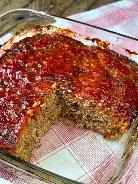 A mostly pan full of ketchup and brown sugar glazed meatloaf showing a moist, meaty filling with oats baked in a glass baking dish. Meatloaf In A Pan, Meatloaf In Cake Pan, 3lb Meatloaf Recipe, Restaurant Meatloaf Recipes, Meatloaf Casserole With Mashed Potatoes, Amish Casserole Recipes, Loaf Pan Recipes Dinners, Dishes Using Ground Beef, Brown Sugar Meatloaf Recipes