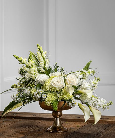 Our white contemporary pedestal design features stunning garden hydrangea, white calla, stock, snapdragons, mountain roses, seasonal fillers and foliage, and presented in a gorgeous gold pedestal for a unique and dramatic display. Trophy Flower Arrangement, White Sympathy Flower Arrangements, White And Green Arrangements, All White Floral Arrangements, White Floral Centerpieces Wedding, Green Floral Centerpieces, Contemporary Arrangements, White Rose Centerpieces, Green Wedding Centerpieces