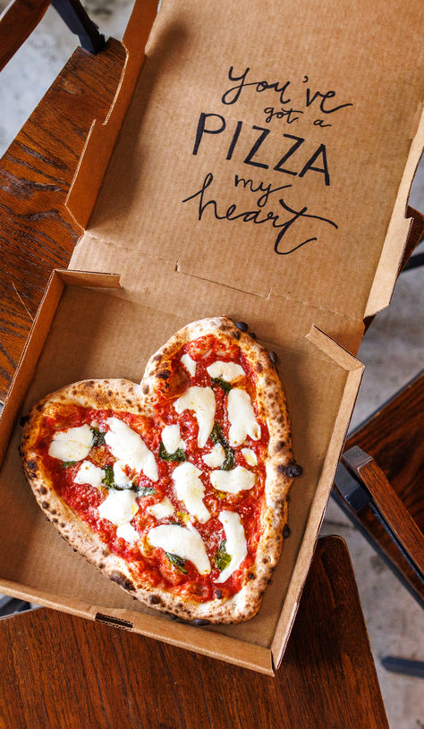 A heart-shaped pizza in a cardboard box on a wooden table. The text on the pizza says "you've got a pizza heart". Pizza Themed Bachelorette Party, Pizza Shop Ideas, Pizza Marketing Ideas, Pizza Truck Wedding, Pizza Heart Shaped, Pizza Engagement Party, Pizzeria Aesthetic, Shaped Pie, Pizza Valentine