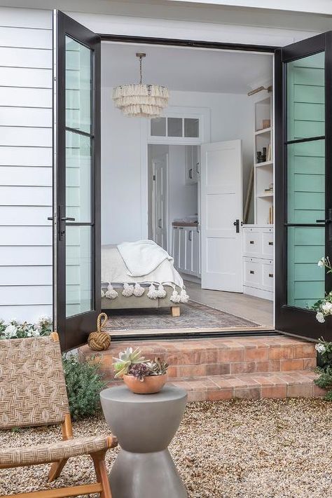 Master bedroom doors to to a backyard open with metal and glass finishings to red brick steps showcasing a furnished space on gravel surface. Christmas Decorations Door, Modern Door Design, Doors Decoration, Christmas Decor Door, Exterior French Doors, Double Patio Doors, Milgard Windows, Sarah Richardson Design, French Doors Exterior