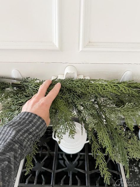 Outside Christmas Garland Ideas, Christmas Wreath Window Outdoor, How To Hang Garland Outside Door, How To Make A Christmas Door Garland, Garland Above Door, Garland On Cabinets, Christmas Garland Around Windows, What To Use To Hang Garland Around Door, Wreath On Hood Vent