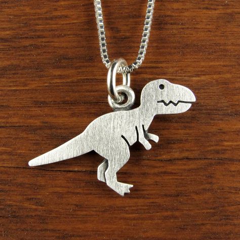 "This fierce little T-rex is made of sterling silver. The pendant is quite TINY, measuring just under 5/8\" tall (1.5 cm) and 7/8\" long (2.1 cm).  Super cute! You can purchase just the pendant/charm, or complete the necklace with a sterling silver box chain (four lengths are available). © Stick Man Creations This is our own original design, handcrafted by us, and signed on the back with our logo.   If you want to read more about the process, click here:  https://www.etsy.com/shop/StickManJewelr Tiny Dinosaur, Dinosaur Pendant, Flatware Jewelry, Dinosaur Necklace, Silver Casting, Man Jewelry, Stick Man, Whimsical Jewelry, T Rex Dinosaur