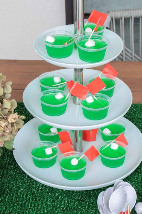 Green golf Jello shots for a gold party. Golf Jello Shots Recipe, Golf Themed Jello Shots, Masters Party Food Ideas, Golf Themed Appetizers, Golf Jello Shots, 50th Birthday Golf Theme, Golf Party Ideas For Men, Golf Themed Food Party Ideas, Golf Dessert Ideas