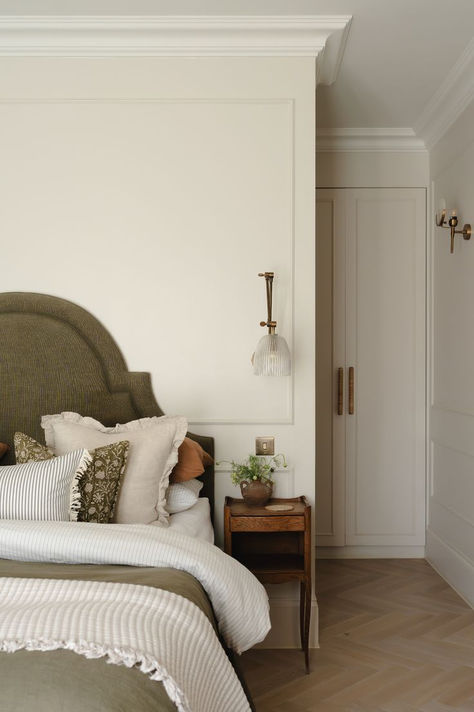 Cozy bedroom with an olive green shapely headboard, layered bedding, and a vintage wooden nightstand for a warm and serene atmosphere. Small Bedroom Ideas Colors, Beige Feature Wall Bedroom, Heritage Bedroom Design, Soho Farmhouse Bedroom, Bedroom With Sconces On Each Side, Bedroom With Beadboard, Cotswolds Bedroom, Organic Luxury Interior, Olive Green Headboard