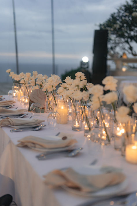 Create an enchanting atmosphere with our white wedding table decoration! Adorn your reception tables with elegant white linens, delicate floral centerpieces, and sparkling candlelight. From classic white roses to modern minimalist designs, find inspiration for your dream wedding table decor on our website. Explore more and follow us for wedding planning tips and ideas! 💍🌿 #WeddingDecor #TableSetting #WhiteWedding #BridalInspiration Wedding Reception Decorations Minimalist, Simply Elegant Wedding Decor, Greenery And White Flowers Wedding Table, Simple Neutral Wedding Table Decor, White Round Table Decor Wedding, Linen Wedding Theme, Minimalist White Centerpiece, Candle Table Arrangements, Single White Roses Wedding Table