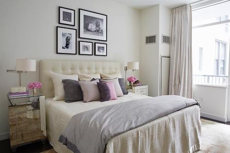 Contemporary bedroom features a black and white photo wall over a cream leather tufted headboard on bed dressed in ivory bedding, gray duvet an assortment of pink, purple and gray pillows flanked by mirrored nightstands situated under polished nickel swing-arm sconces with drum shades. Tufted Headboard Bedroom Decor, Cream And Pink Bedroom, Tufted Headboard Bedroom, Small Space Storage Bedroom, Light Pink Bedrooms, Cream And White Bedroom, Blush Pink Bedroom, Beige Headboard, Leather Bedroom