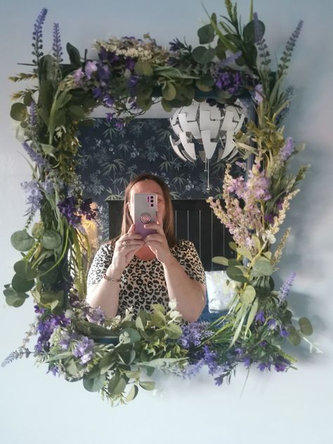 DIY mirror. I painted my Plain wood mirror dark blue then stapled artificial flowers to it to match the wall power on the opposite wall. Took about 1 hour to make and I think it really pulls the room together Mirror Decorated With Flowers, Diy Fairy Mirror Frame, Moss And Flower Mirror, Plant Mirror Frame, Dried Flower Mirror, Diy Mirror Frame Ideas Flowers, Mirror With Plants Around It, Mirror With Flowers Around It, Flower Theme Room