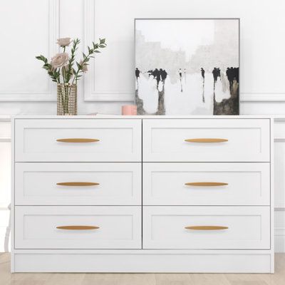 This double dresser is a versatile storage solution that combines functionality and style. Made from engineered wood, it features six spacious drawers with smooth roller glides for easy access to your clothes, bedding, or other household items. The gold-finished handles and inset paneling give it a chic and elegant touch. Plus, this dresser can double as a console table in your hallway or entryway. With a finished back and tip-over restraint device included, it ensures safety while maintaining a Dressers Wood, Closet Dressers, White Dressers, Dresser Wood, White Dresser, Wood Handles, Bedroom Furniture Dresser, Double Dresser, 6 Drawer Dresser