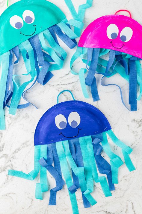 Bright, cute Jellyfish created out of a paper plate are an easy kids craft that they will love making. Grab your craft supplies and create this easy paper plate craft. Not only will the kids love making this jellyfish craft, but they will brighten up your house when they display them. Ocean Art Projects For Kids Toddlers, Rainbow Fish Paper Plate Craft, Easy May Crafts For Kids, Toddler Spring Crafts Easy, Paper Plate Jelly Fish Craft, Paper Plate Mermaid Craft, Paper Plate Spring Crafts, Star Fish Craft For Toddlers, Jellyfish Paper Plate