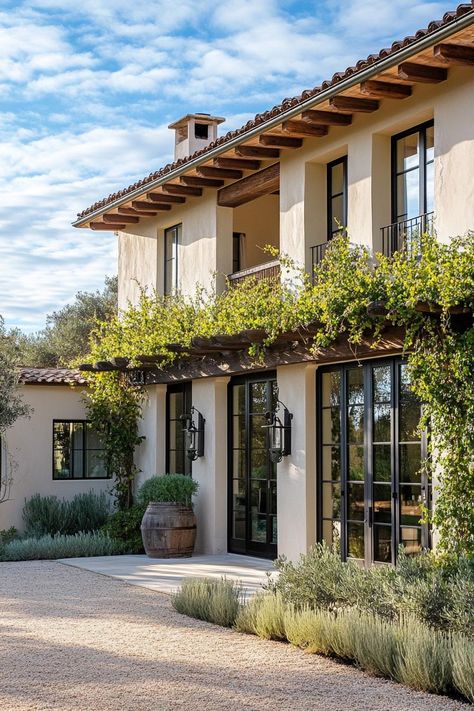 Modern Italian mediterranean house facade with vine covered pergola olive tree lined front yard. Check out all of these stunning Italian Mediterranean houses that encapsulate elegant arches, textured stucco, charming terra cotta details, and so much more. Spanish Home Windows, Santa Barbara House Style, Italian Inspired House Exterior, Elegant Mediterranean Homes, European House Style, Modern Spanish Colonial Exterior, French Italian Homes, Spanish Revival Courtyard, Desert Mediterranean Home