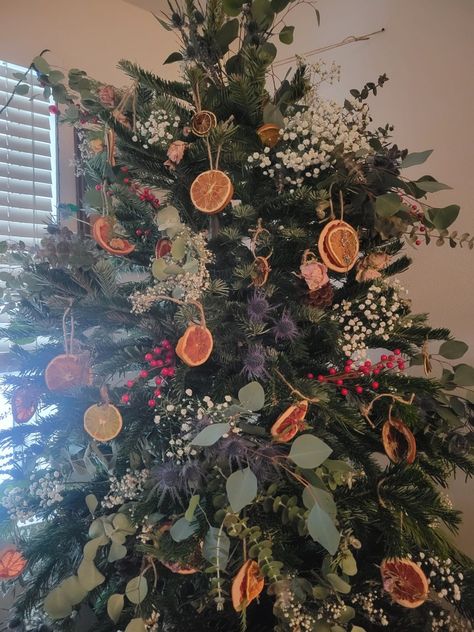 Christmas tree decorated with flowers and dried citrus! Tree Decorated With Flowers, Dried Fruit Christmas Tree Decorations, White Christmas Tree Vintage, Christmas Tree Ideas Eclectic, Dried Flowers In Christmas Tree, Christmas Tree With Cranberry Garland, Dried Fruit Holiday Decor, Yule Themed Christmas Tree, Non Ornament Christmas Tree