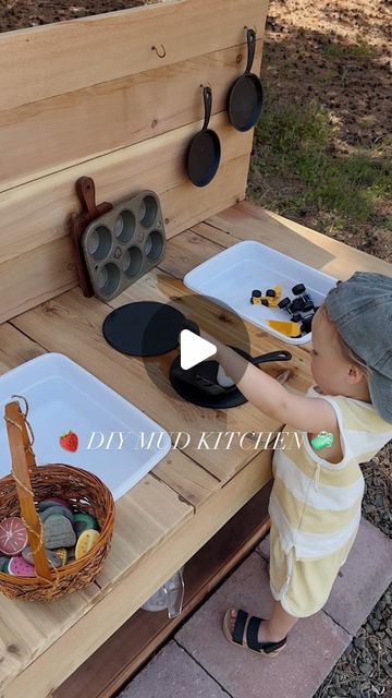 Kylie Morgan on Instagram: "🧼 A DIY SCRAP WOOD MUD KITCHEN 🍓  I think this has been my favorite (and quickest & cheapest) project for Remy thus far! 🥹 (only took about two hours!)   I've been seeing mud kitchens all over Pinterest and have been wanting to build one for him this summer! We lucked out and had a bunch of leftover scrap wood from projects & the previous owners of this house have left a bunch behind randomly 🪵 (it was built with 2x4's & plywood though, so easy!!)   Chase is quicker at this all than me, so he threw it together & I did a little sand & style and I'm OBSESSED 🥹   The little thrifted muffin tin & cast irons, and the hand painted fruit and veggie rocks are my fave 🥑🌽🍓🌟   🧼 All the things to make your mud kitchen complete for fun all summer long:  + 2x4's & Sandbox Mud Kitchen, Diy Pallet Mud Kitchen Outdoor Play, Diy Mud Table For Kids, Mud Kitchen Diy How To Build, How To Build A Mud Kitchen, Mud Kitchen Painted Rocks, How To Make A Mud Kitchen, Easy Mud Kitchen Diy, Mud Table For Kids