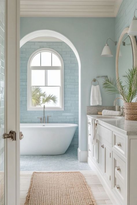 Bring the beach into your bathroom with coastal-inspired decor. Use light, airy colors like white and blue, incorporate natural elements like shells and driftwood, and choose light, breezy fabrics. 🌊🏖️ Light Blue White Bathroom, Blue And White Floral Bathroom, Beach House Bathroom Aesthetic, Spa Coastal Bathroom, Bathroom With Light Blue Walls, Blue Coastal Bathroom Ideas, Beach Bungalow Interior Coastal Cottage, Elegant Blue Bathroom, Cute Colorful Bathroom