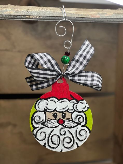 "NEW FOR 2023!! LIMITED QUANTITIES!! Hand-painted Santa Face Round Ornament is a fun addition to your Christmas tree. This hand-painted wood round ornament has a custom, beaded wire hanger and black and white checked bow. Comes fully assembled and ready to hang on the tree.  Ornament size: 5\"H x 4\"W x 1/4\"D; Hanging height: 8.75\"" Acrylic Painted Ornaments, Wood Cutout Ornaments, Glass Painted Ornaments, Handpainted Wooden Christmas Ornaments, Christmas Vacation Painting, Hand Painted Wooden Ornaments, Hand Painted Wreath Ornaments, Painted Ornament Ideas, Christmas Painted Ornaments