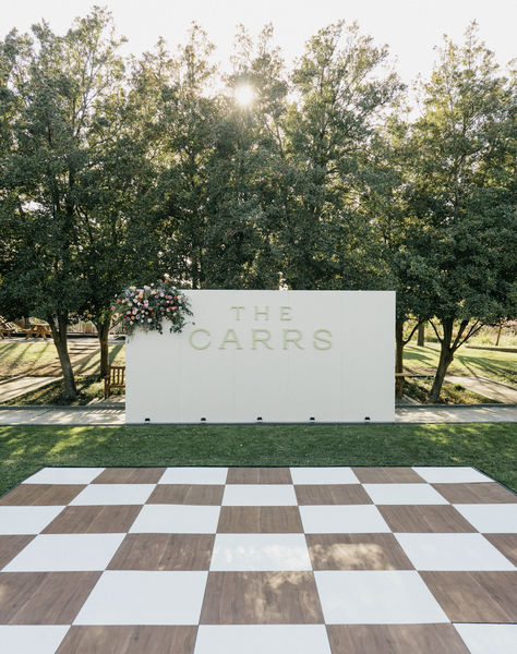 Wooden and white checkered dance floor with stunning custom wall! Perfect for welcoming guests to dance!! Stunning and unique flooring for Dallas wedding!  #socialllamaevents #dallaswedding #dancefloor #customdancefloor #weddingrentals #weddingdeocr #weddinginspo #weddingfloor #customrentals #dallasrentals #customwedding #socialllama #customrentals #weddinginspiration Outdoor Reception Dance Floor, Checkers Dance Floor, Wedding Decor Dance Floor, Wedding Dance Floor Alternatives, Wedding Floor Vinyl, How To Build A Dance Floor, Checkered Dance Floor Outdoor Wedding, Wooden Dance Floor Wedding, Diy Checkered Dance Floor