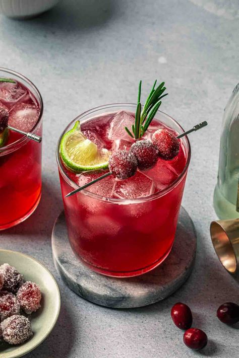 Made with cranberry juice, maple syrup and a splash of ginger beer, this Christmas gin cocktail is crisp and refreshing. We've garnished it with fresh rosemary and sugared cranberries for a festive, vibrant cocktail that will be the hit of your holiday gathering. Cocktail With Rosemary, Cranberry Ginger Beer Cocktail, Christmas Cocktail Garnish Ideas, Gin Punch Recipe Easy, Christmas Cocktail Garnish, Gin Christmas Cocktail, Christmas Gin Cocktails, Cranberry Gin Cocktail, Gin Punch Recipe