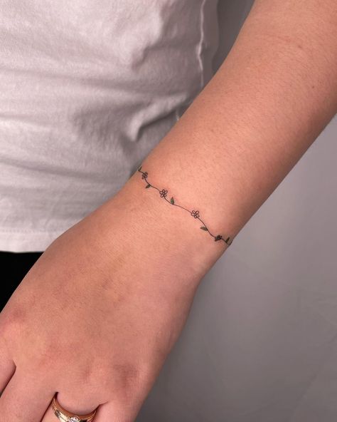 60+ Best Daisy Tattoo Ideas & All You Must Know About Them - InkMatch Daisy Chain Anklet Tattoo, Daisy Ring Tattoo, Dainty Flower Chain Tattoo, Daisy Chain Tattoo Wrist, Flower Vine Bracelet Tattoo, Constellation Wrap Around Tattoo, Simple Anklet Tattoo, Cute Bracelet Tattoos, Delicate Daisy Tattoo Simple