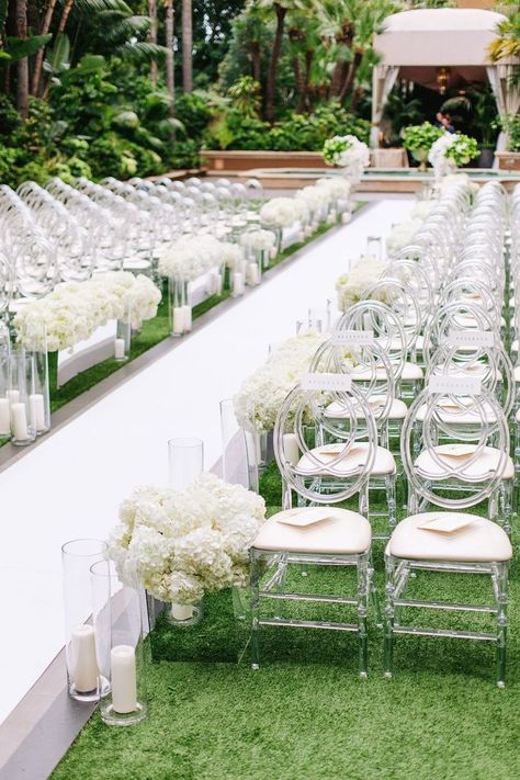 Dec 21, 2020 - Guests found their seats on oval-back acrylic chairs on both sides of a crisp white aisle lined with candles and arrangements of ivory hydrangeas in mirrored b… Sleek And Modern Wedding, Outside Wedding Ceremonies, White Hydrangea Wedding, Wedding Ceremony Chairs, White Wedding Ceremony, Ceremony Florals, White Wedding Decorations, Wedding Isles, Hydrangea Wedding