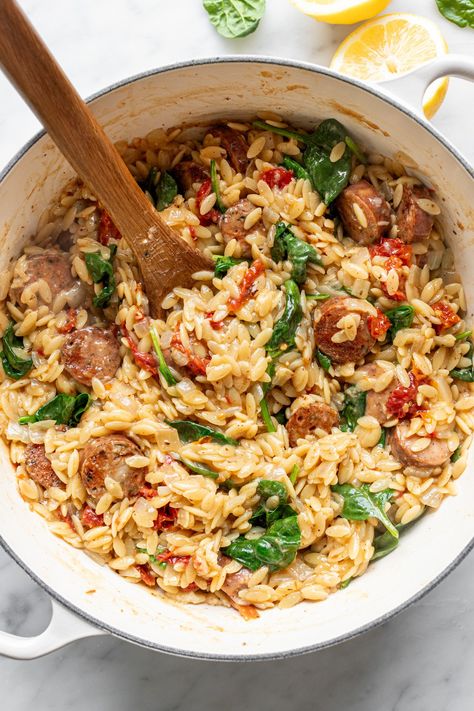 This rich, umami sun dried tomato orzo is cooked in one pot with spinach, precooked chicken sausage, garlic, broth and a topping of parmesan cheese, lemon juice, and basil. This is a lick-your-bowl-clean meal, through and through. One Pot Meals With Orzo, One Pot Sausage Orzo, Sausage Orzo Spinach, Sun Dried Tomato Orzo Chicken, Summer Orzo Recipes, Tomato Basil Chicken Sausage, Orzo And Chicken Sausage Recipes, Creamy Chicken Sausage Orzo, Rotel Sausage Pasta