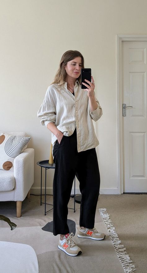 A woman stands in front of a mirror. She wears a black cord necklace, ecru oversized shirt with the sleeves pushed up, black cropped trousers and beige and orange New Balance sneakers. Crop T-shirt Outfits, Women’s New Balance 574 Outfit, Oversize Outfits Woman, Casual New Balance Outfit, New Balance Office Outfit, New Balance Style Women Outfits, Black Pants And Sneakers Outfit, New Balance 574 Black Outfit, Cute Outfits With New Balance