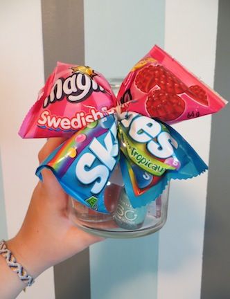 CANDY BOW: Pinch the middle of 2 packs of her favourite candy and secure with a wire twist-tie. Add an elastic to hold it around the top of the jar.   JAR CONTENTS: Votive sized candle, nail polish, hand sanitizer, chewing gum, lip balm, earrings, a couple Starbucks Via packets, and a couple Crystal Light On-the-Go packets...That's 11 things in 1 jar!   I got the jar from a second-hand store, it's approximately 4 inches wide and 5 1/2 inches tall. Cheer Sister Gifts, Sister Gifts Diy, Bows For Presents, Diy Christmas Gifts For Kids, Cheer Team Gifts, Secret Sister Gifts, Christmas Bows Diy, Cheer Spirit, Cheerleading Gifts