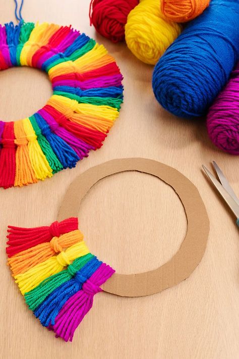 Make a rainbow tassel wreath using colourful yarn and a piece of cardboard! This rainbow craft is SO EASY to make, perfect for kids of all ages and adults. This homemade decor looks so beautiful on display, and you can make it using simple craft supplies. Holiday Yarn Crafts, Tassel Wreath, Diy Yarn Decor, Craft For All Ages, Door Toran, Yarn Crafts For Kids, Easy Yarn Crafts, Rainbow Craft, Make A Rainbow