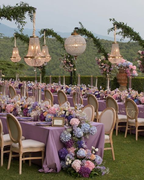 Omg, this stunning setting for Paul and Elicia’s rehearsal dinner is pure magic! 🌸✨ Lavender tablescapes adorned with lush hydrangeas and roses, under sparkling chandeliers. #eventigaia #weddingplanner #wedding #weddinginspiration #RehearsalDinner #WeddingDecor #FloralFantasy Lavender Nikkah Decor, Lavender Event Decor, Lavender And Pearl Wedding, Purple Romantic Wedding, Pastel Blue And Purple Wedding Theme, Lavender And Blush Wedding Theme, Lavender Fields Wedding, Purple Wedding Venue Decorations, Lavender Reception Decorations