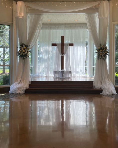 Getting ready for a ceremony at the altar with cross with drapery accent and beautiful flower tie backs. #houseestate #indoorceremony #houstonweddings Wedding Crosses Altar, Altar Wedding Indoor, Wedding Altar Indoor, Cross Altar Wedding, Altar Flowers Wedding, Wedding Alters, Altar Flowers, Wedding Cross, Flower Tie