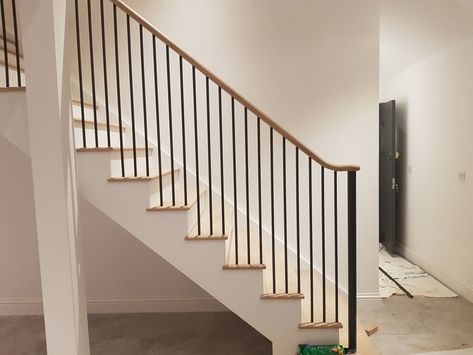 Fitting in progress for this staircase featuring round metal spindles and a continuous handrail. Iron Railing Staircase, Black Wood Spindles Staircase, Staircase Metal Spindles, Stairs With Metal Spindles, Black Metal Spindles Staircase, Staircase Spindle Ideas, Metal Spindles Staircase, Iron Spindle Staircase, Remodel Staircase