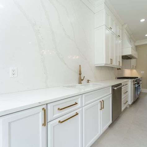 Full wall backsplashes are made to harmonize the countertops and backsplash with the entirety of the kitchen. Just look at that perfect symphony of whites and gentle marble-looking veining -- so elegant and beautiful! 🌿 

Contact us today for your quartz countertops + quartz backsplash combo. 🙌 

#howwedwell #kitchendesign #whitecabinets #kitchenmakeover #standoutstyling
#kitchenenvy #smmakelifebeautiful #thedelightofdecor #dailydecordose #whiteandgold #customkitchen #quartzbacksplash Solid Marble Backsplash Kitchen, Kitchens With Marble Backsplash, Full Height Backsplash Quartz, Backsplash Kitchen Quartz, White Marble Backsplash Kitchen, Backsplash With Quartz Countertop, Full Wall Backsplash, Best Quartz For White Cabinets, White Marble Kitchen Backsplash