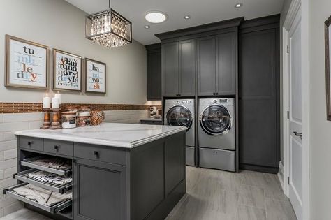 Charming gray laundry room boasts a gray front loading washer and dryer enclosed beneath and between dark gray cabinets accented with matte black hardware. Laundry Room Island, Laundry Room Countertop, Grey Laundry Rooms, Laundry Room Storage Shelves, Room Storage Diy, Stylish Laundry Room, Basement Laundry Room, Dream Laundry Room, Basement Laundry