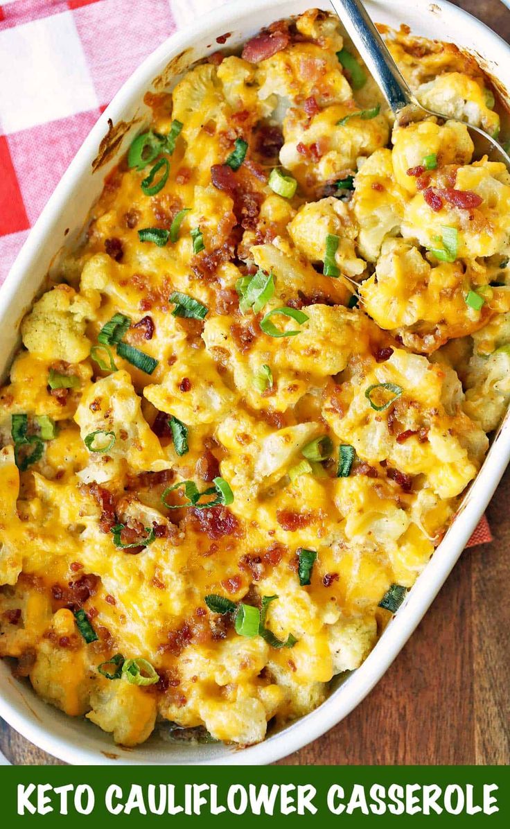 a white casserole dish with green onions and cheese in it on a checkered tablecloth