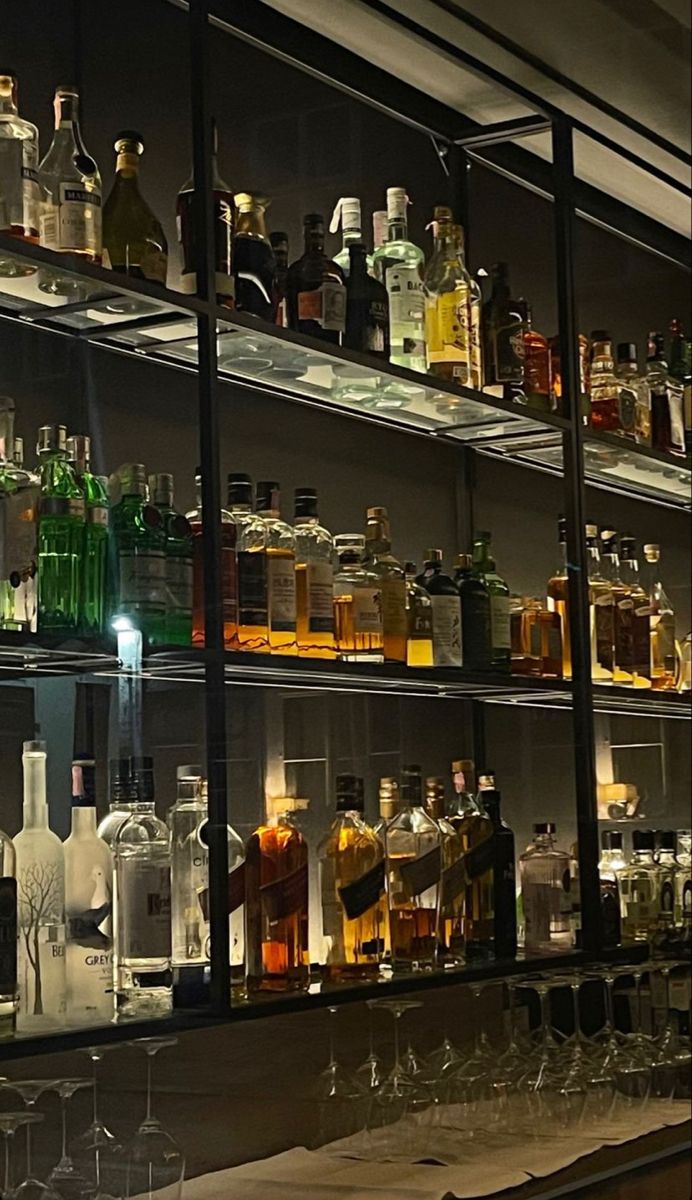 many bottles and glasses are lined up on the shelves