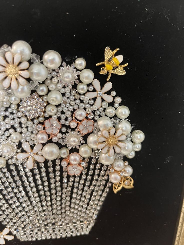 a close up of a hair comb with pearls and flowers on the front, and a bee brooch in the back