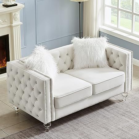 a white couch sitting in front of a fire place next to a lamp and window