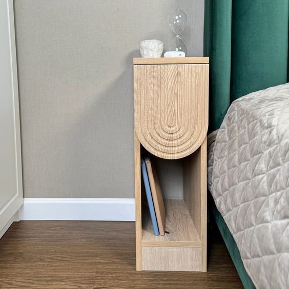 a small wooden shelf next to a bed