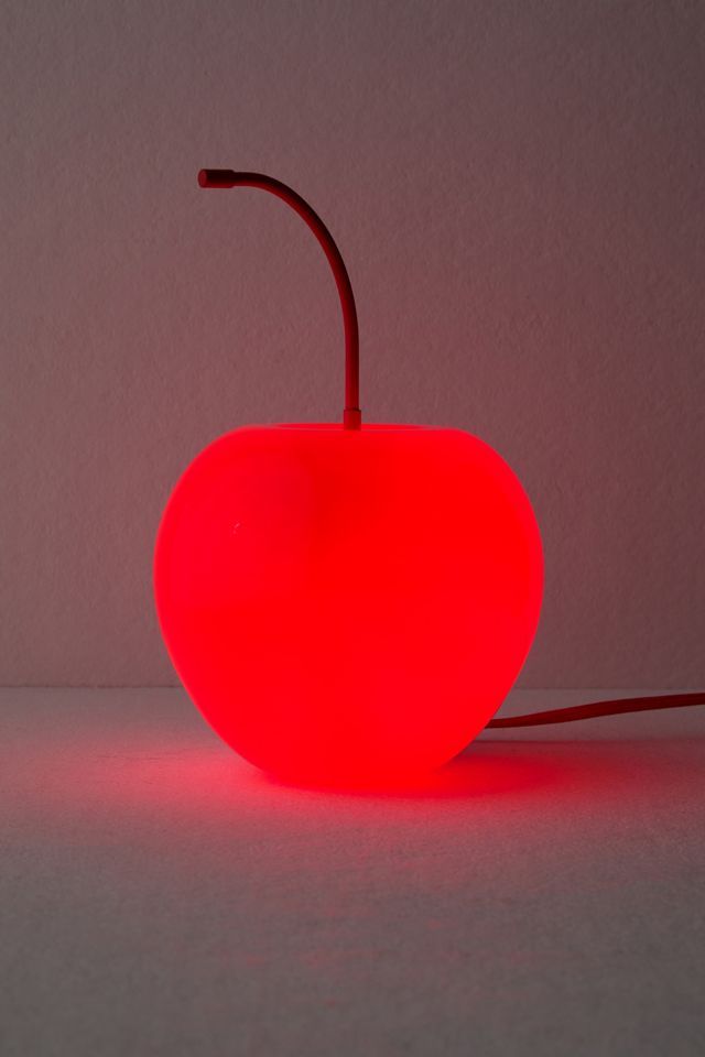 a red apple shaped lamp sitting on top of a table