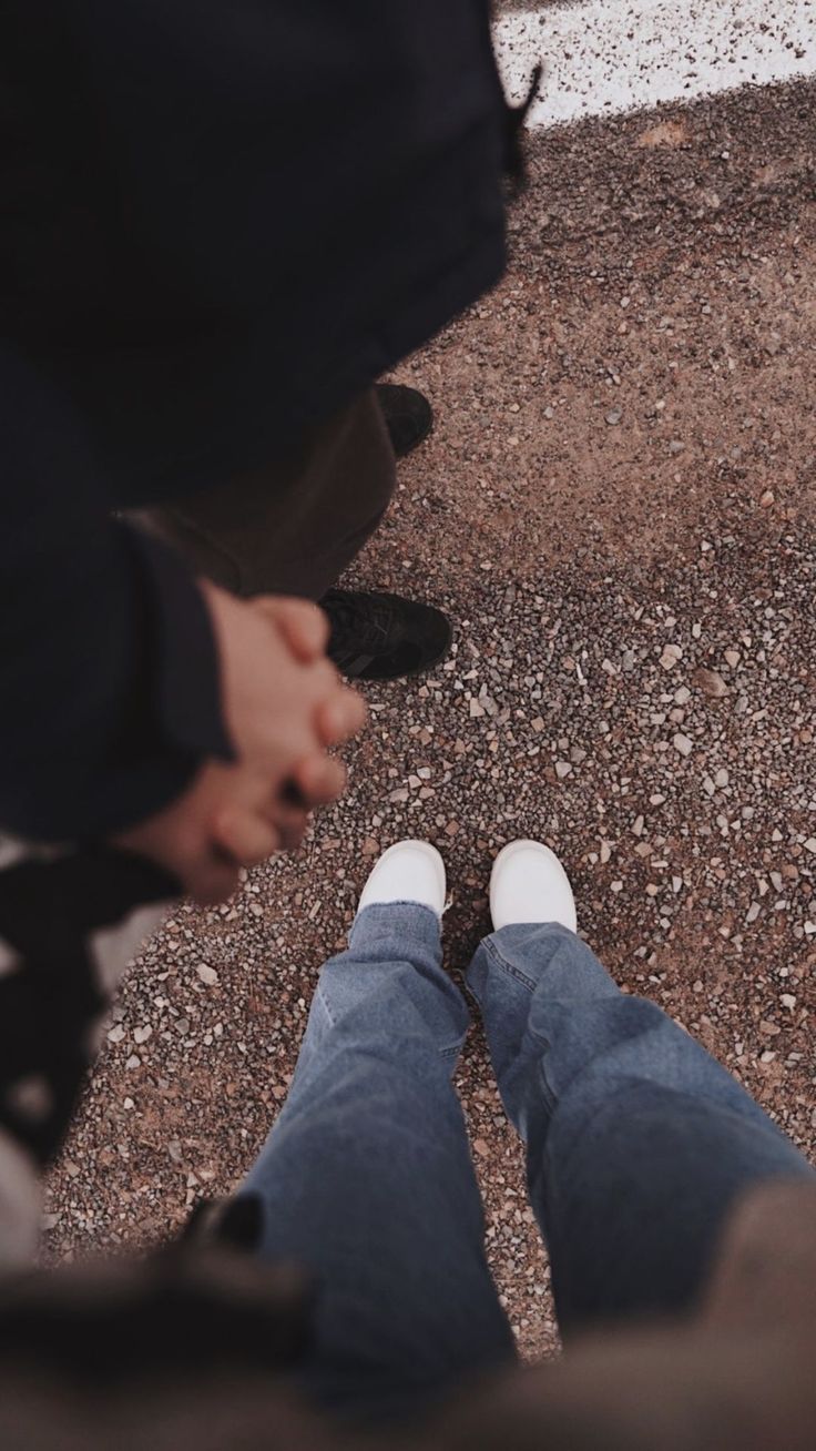 two people standing next to each other with their feet on the ground and one person wearing white shoes